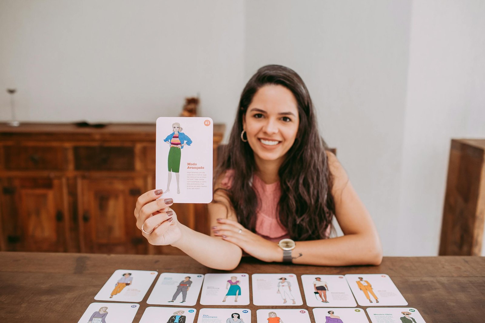 Smiling woman presenting educational flashcards at a wooden table indoors.